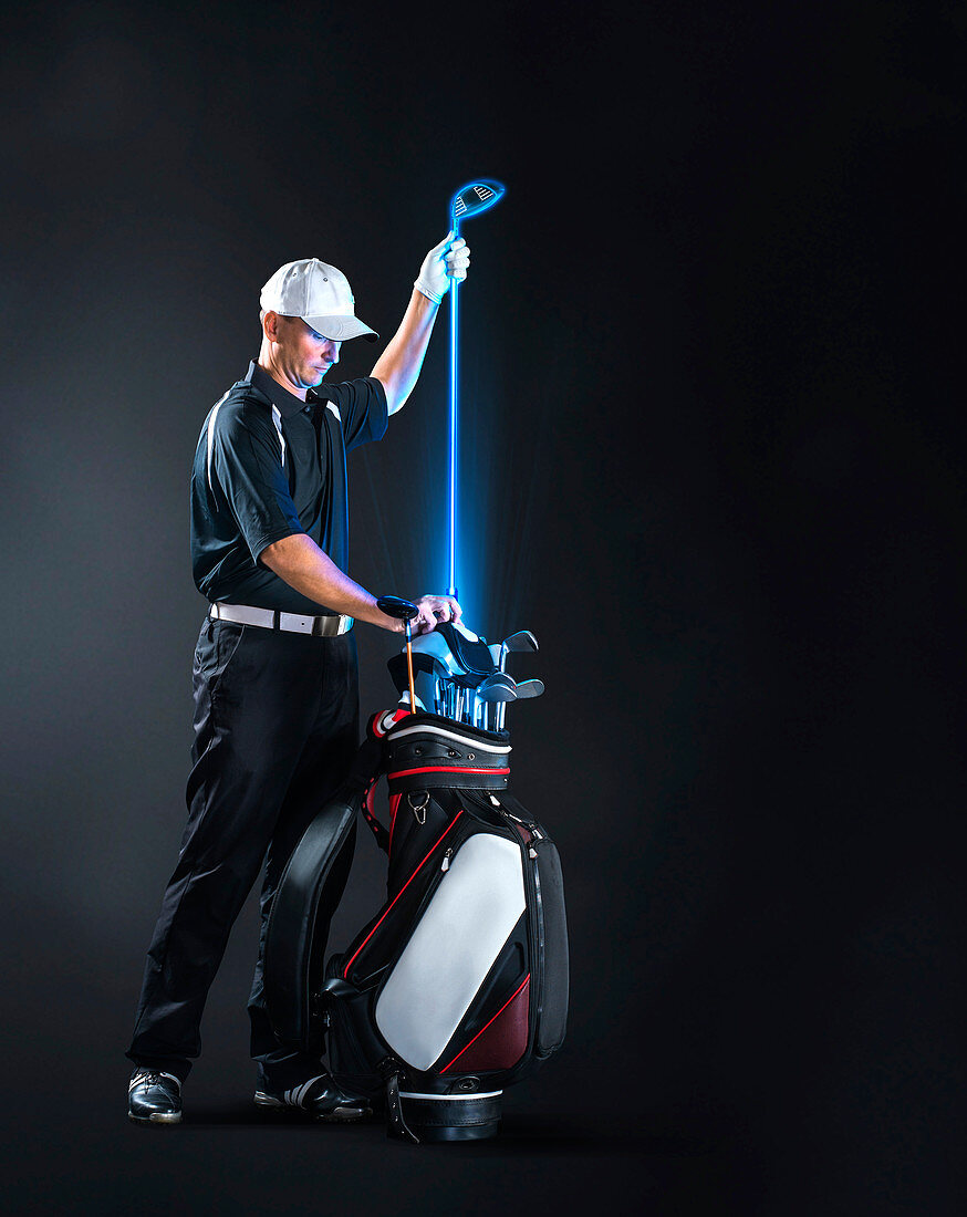 Male golfer removing glowing golf club from bag