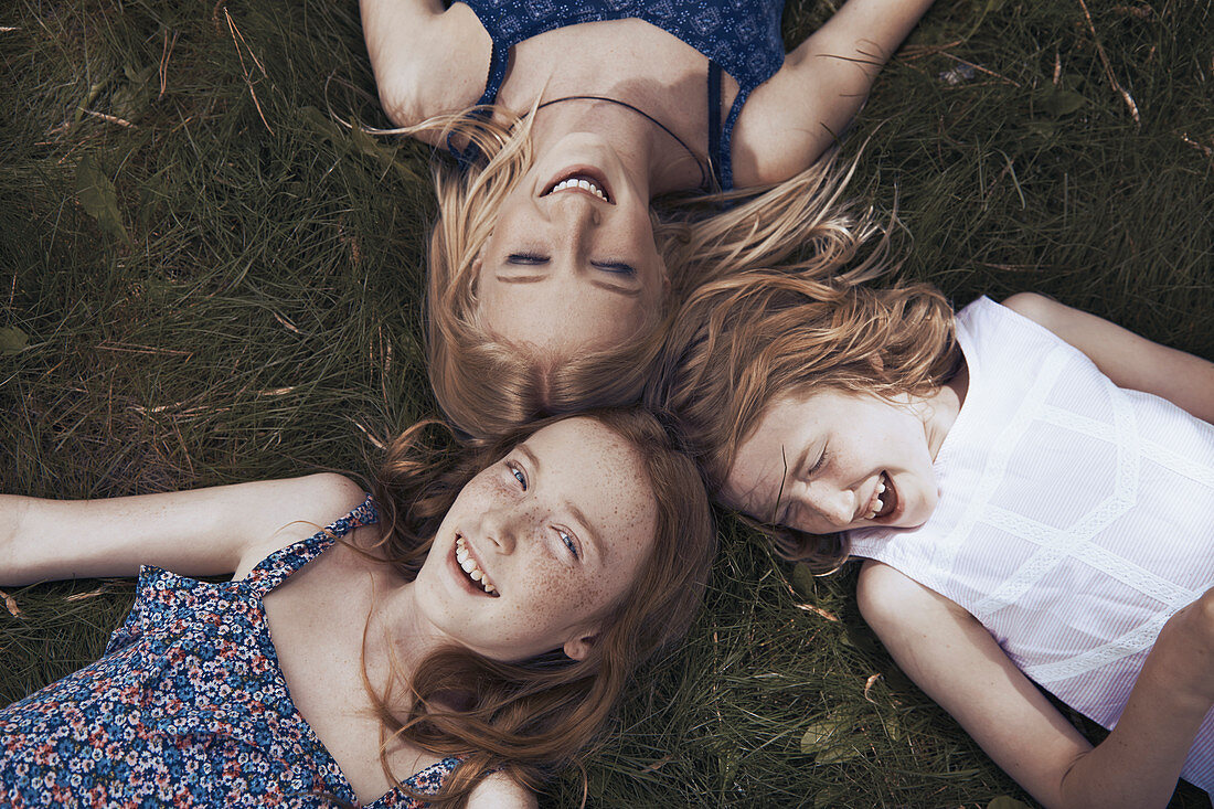 Portrait happy sisters laying in grass