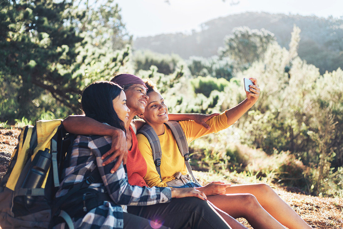 Happy mother and daughters taking selfie, hiking