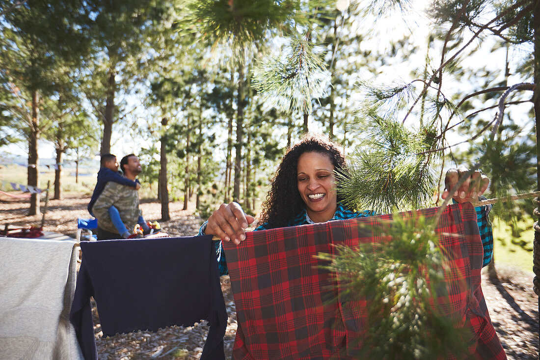 Smiling woman hanging clothing in woods