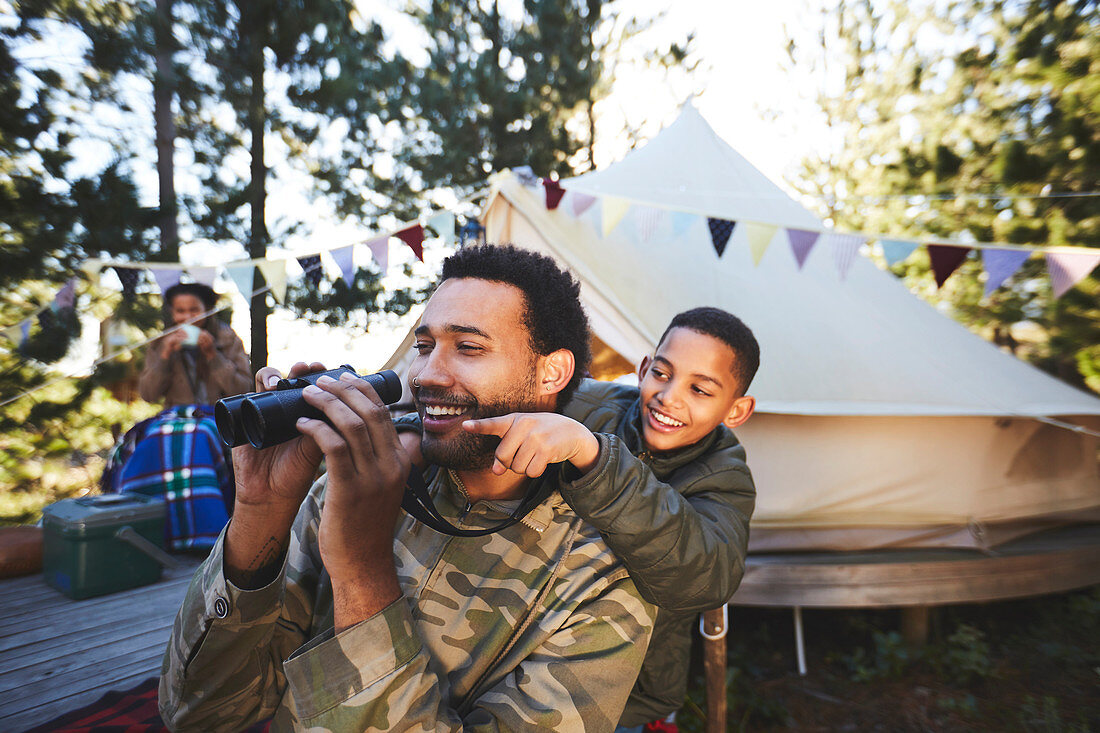 Father and son with binoculars at campsite