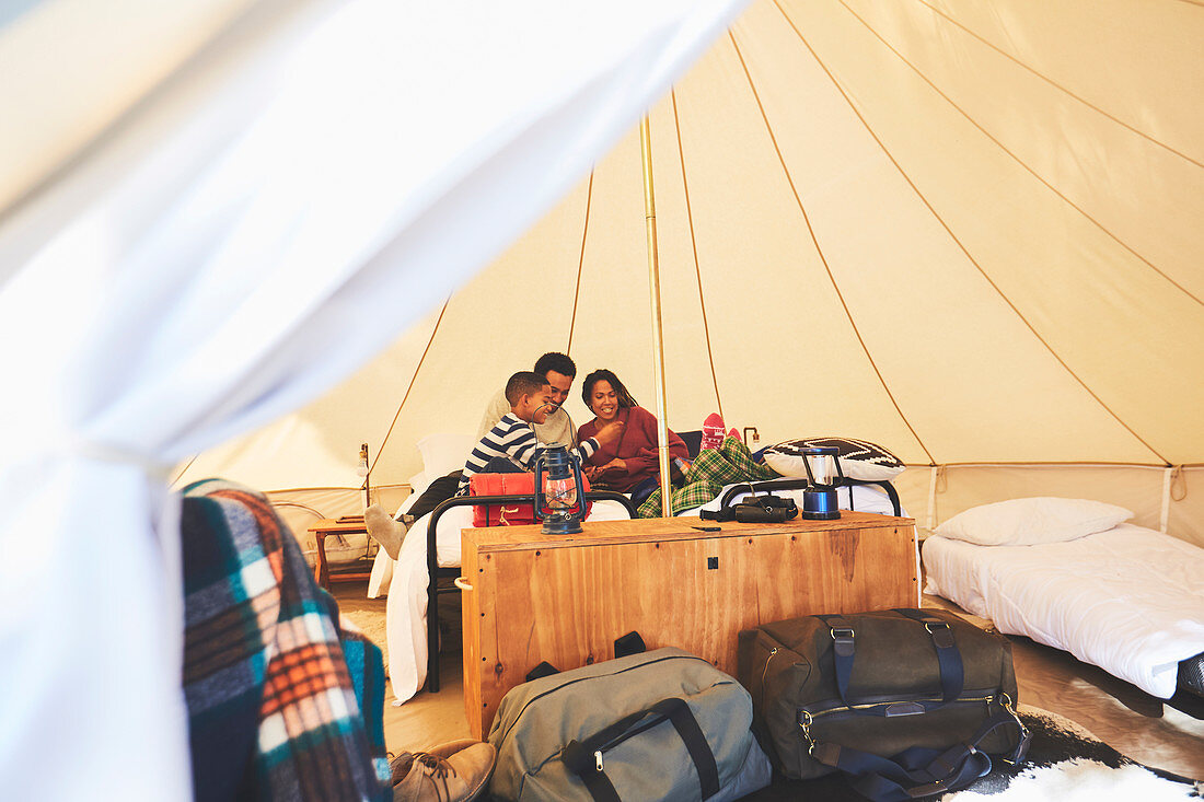 Family relaxing on bed inside camping yurt