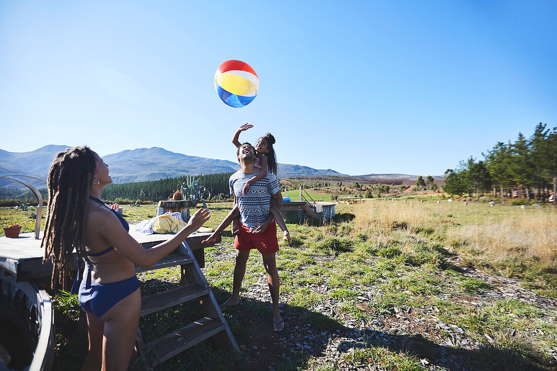 Happy, playful family with beach ball in field