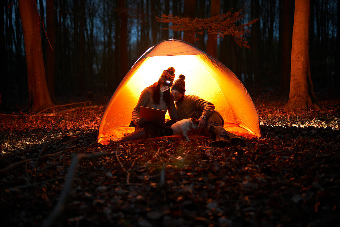 Couple using digital tablet inside glowing tent