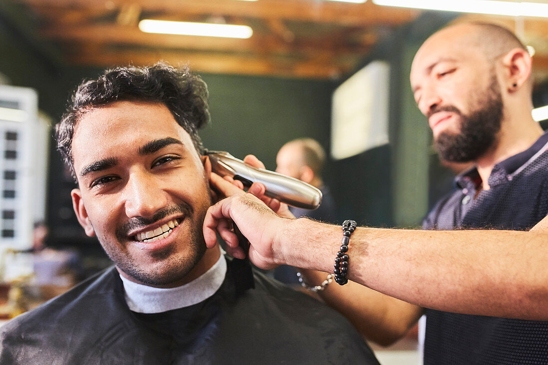 Portrait smiling young man receiving haircut