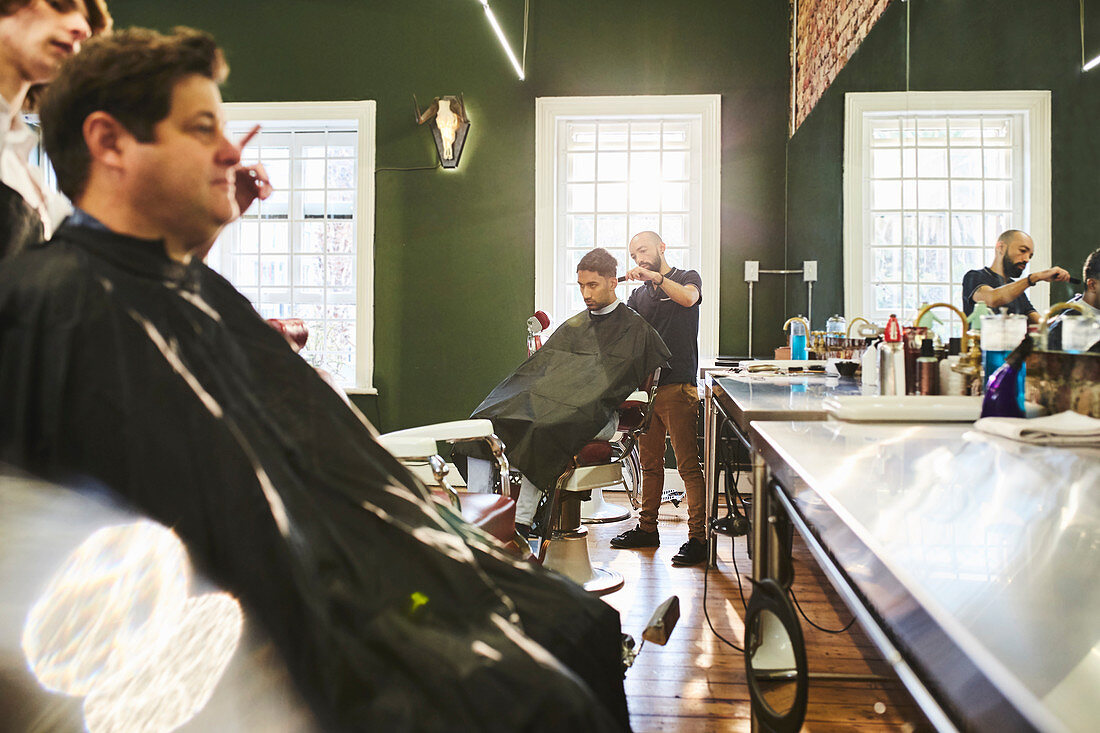 Male customers and barbers in barbershop