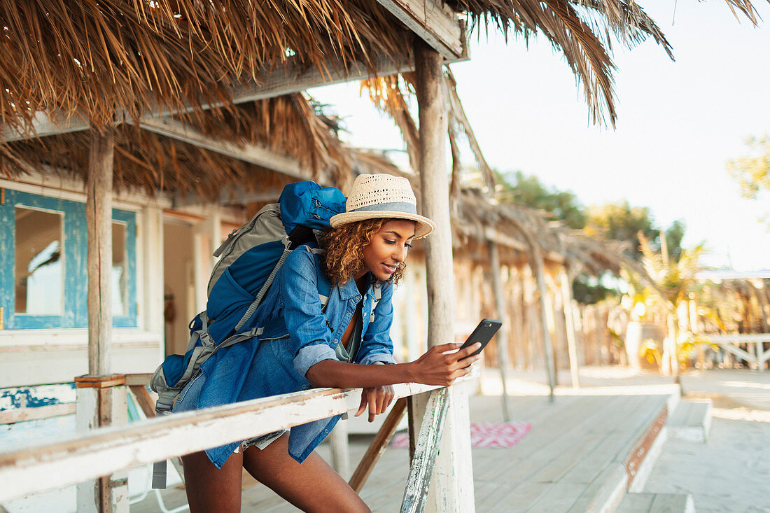 Young female backpacker on beach hut patio