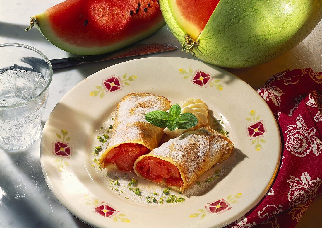 Crepes with melon filling, icing sugar and cream on plate