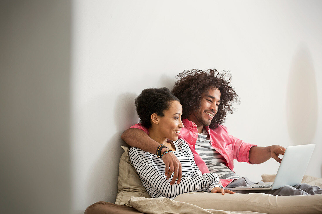 Happy, couple using laptop on bed