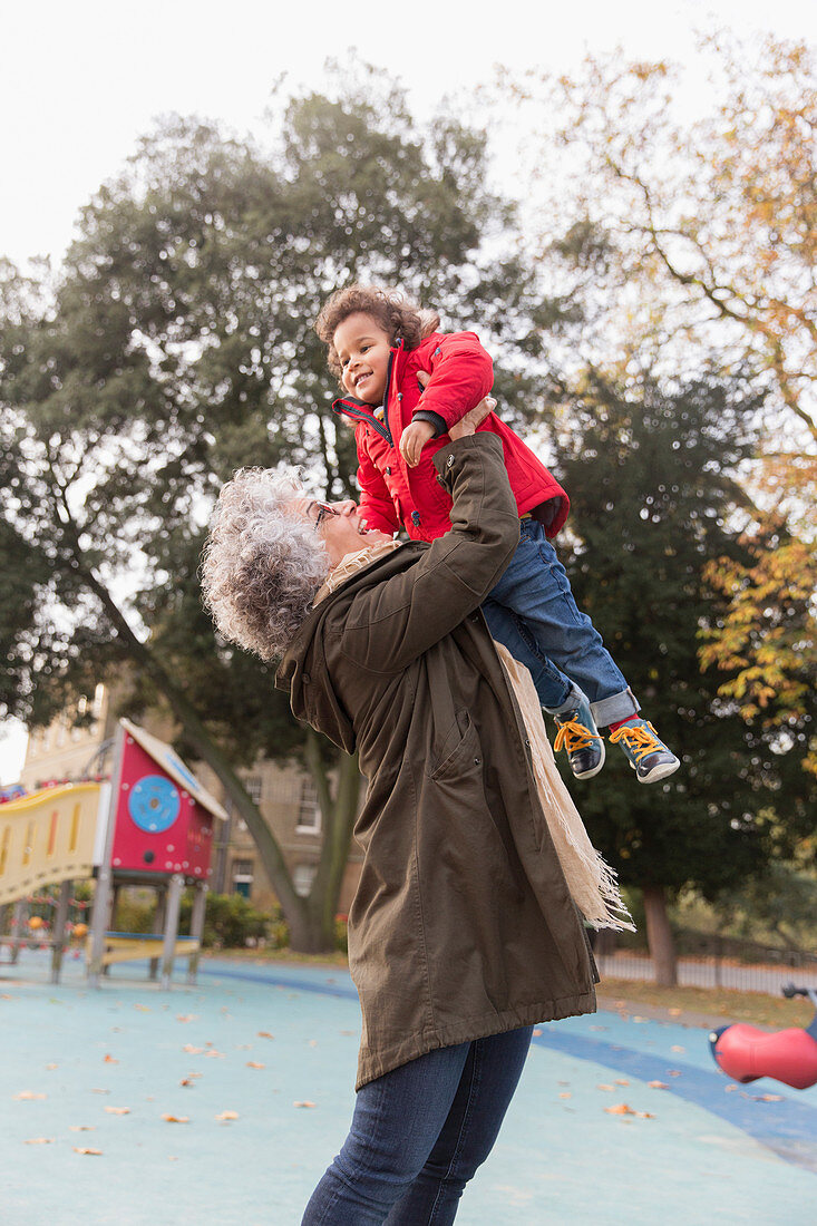 Grandmother lifting granddaughter at playground