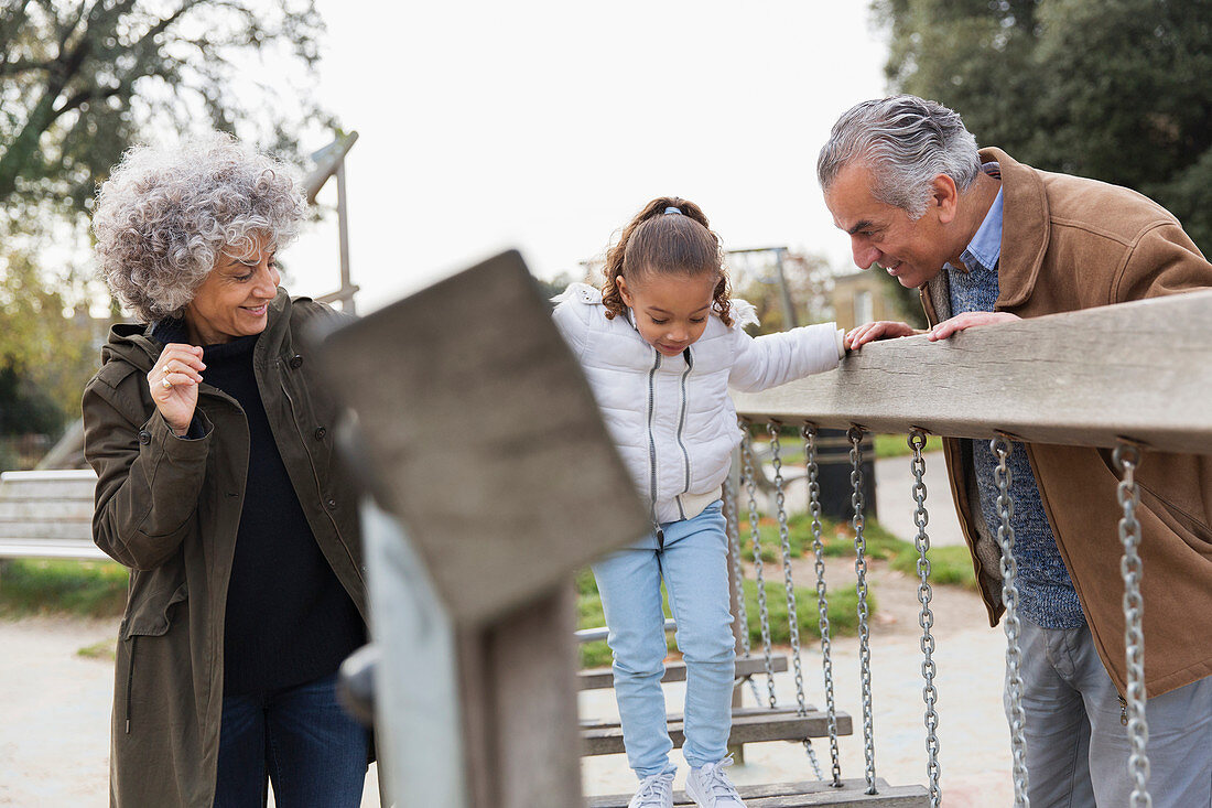 Grandparents and granddaughter playing at playground