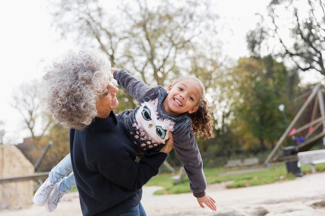 Grandmother lifting granddaughter at playground