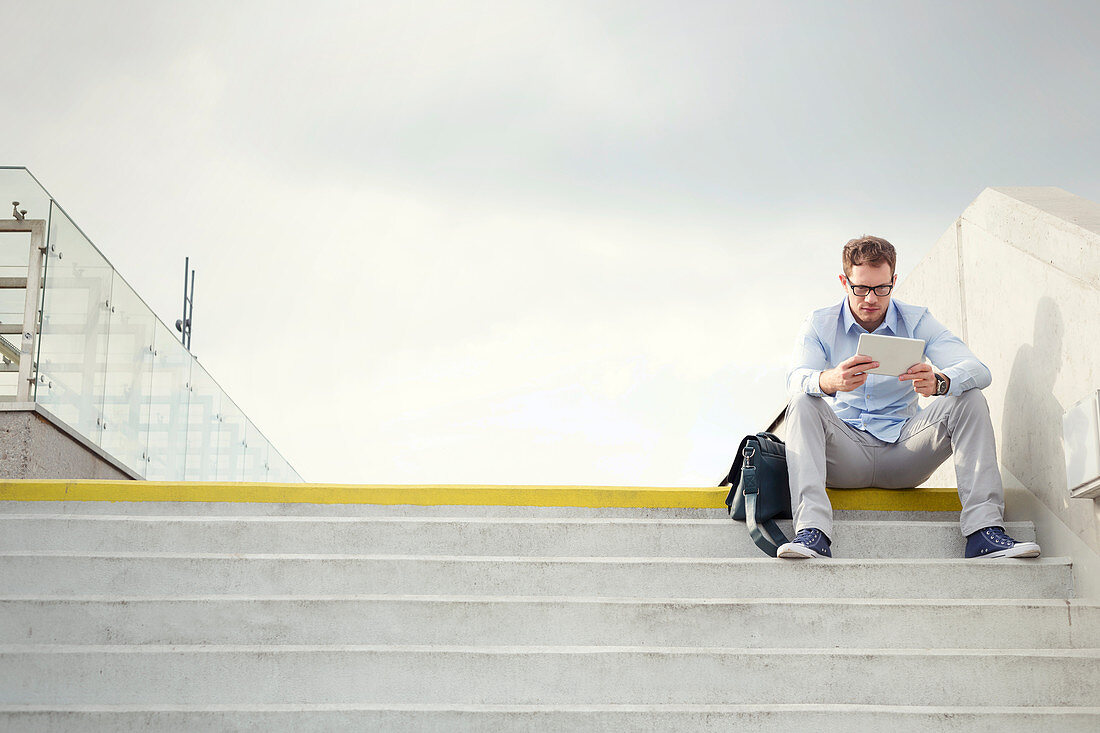 Businessman using digital tablet on urban steps