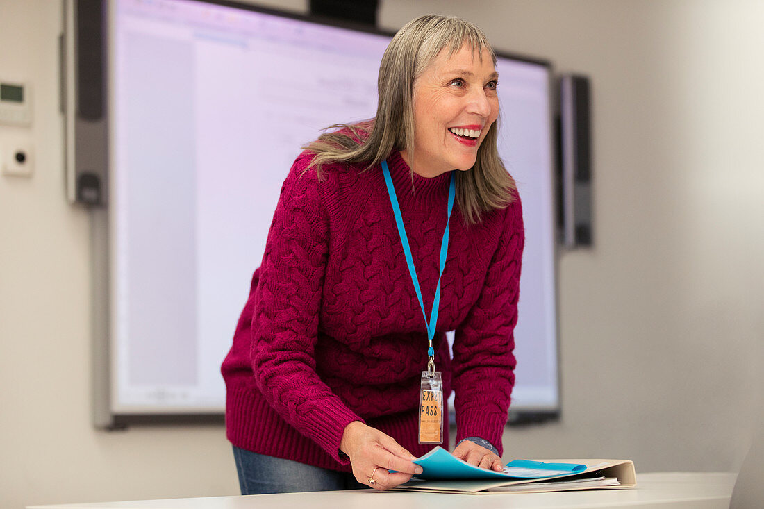Confident, happy female instructor preparing in classroom