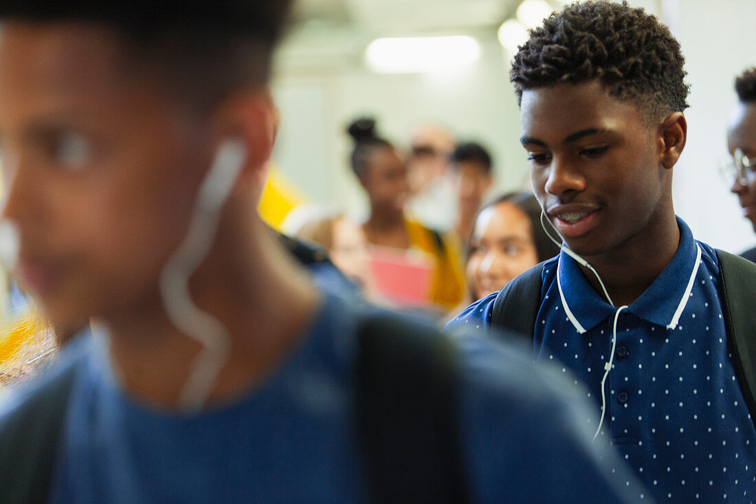 Junior high boy student with headphones in corridor