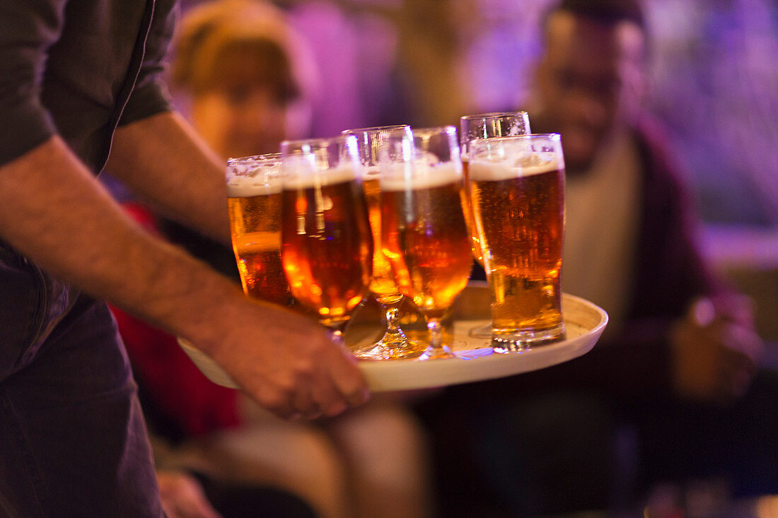 Man serving tray of beers to friends