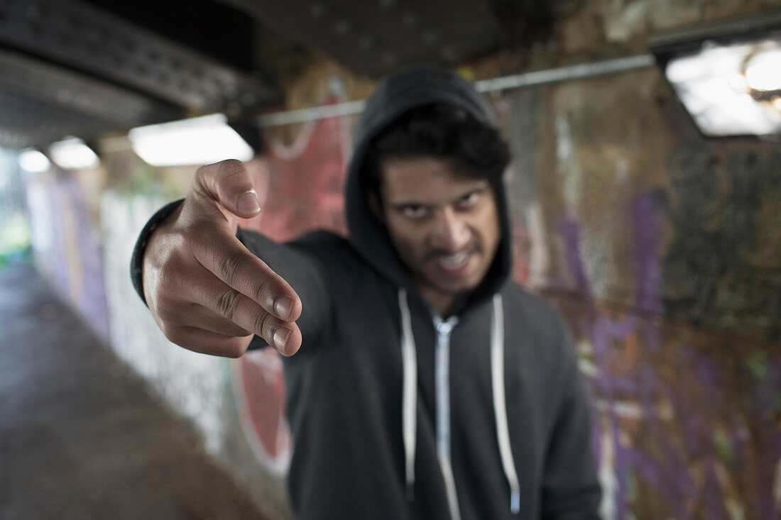 Portrait menacing man gesturing finger gun in urban tunnel