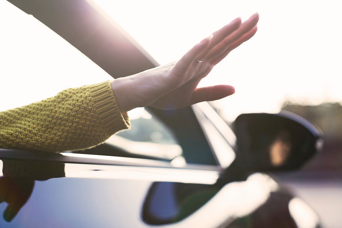 Carefree woman reaching hand out car window