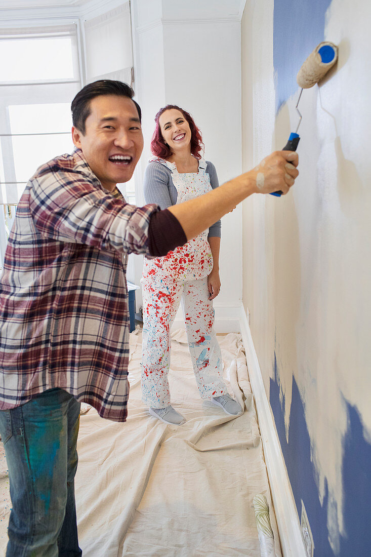 Portrait happy couple painting wall