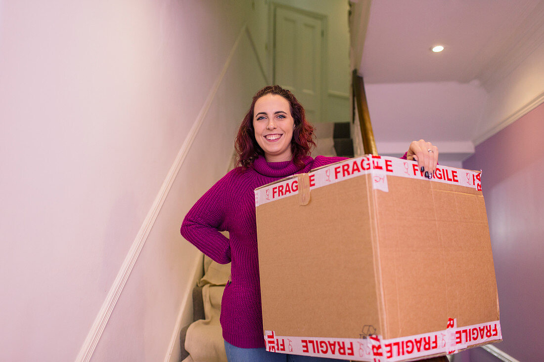 Woman moving into new home, carrying cardboard box
