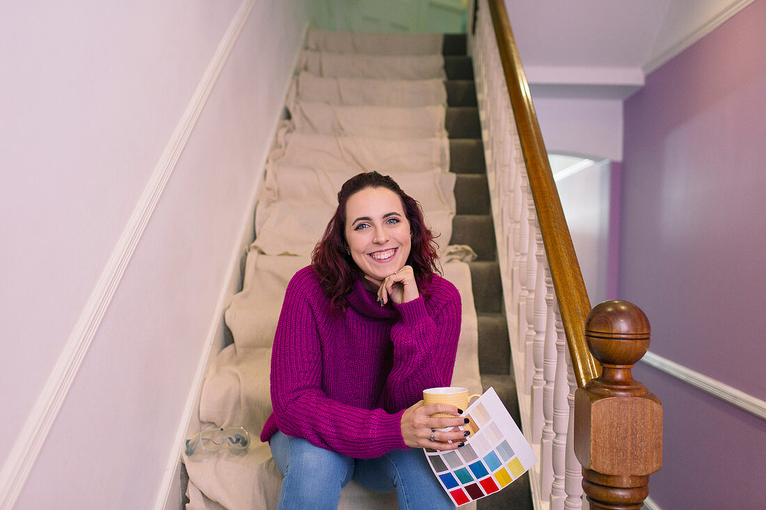 Woman redecorating, holding paint swatch on stairs
