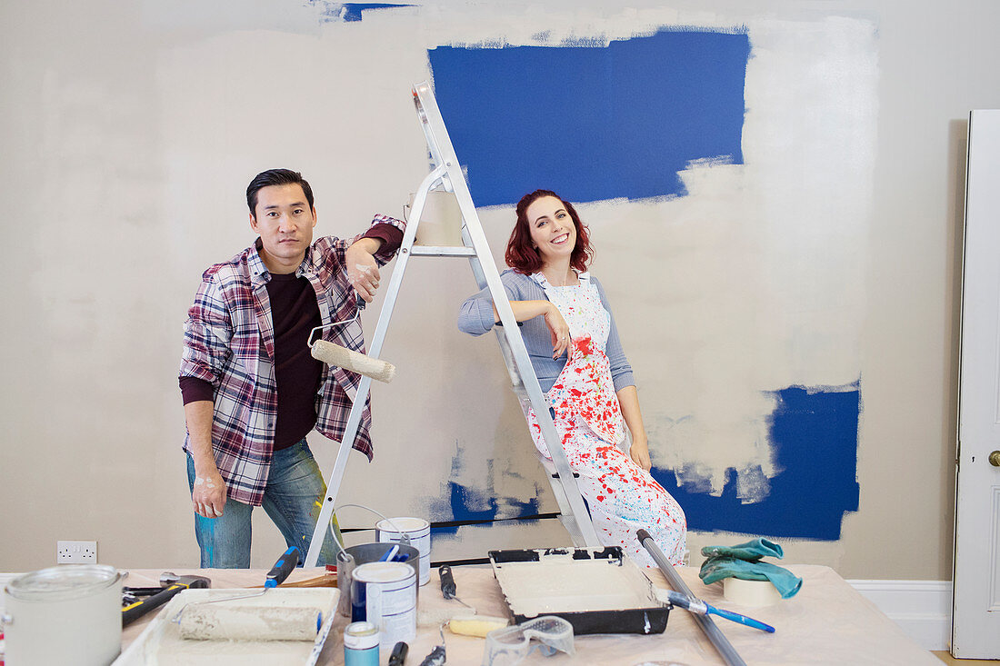 Portrait couple redecorating, painting wall