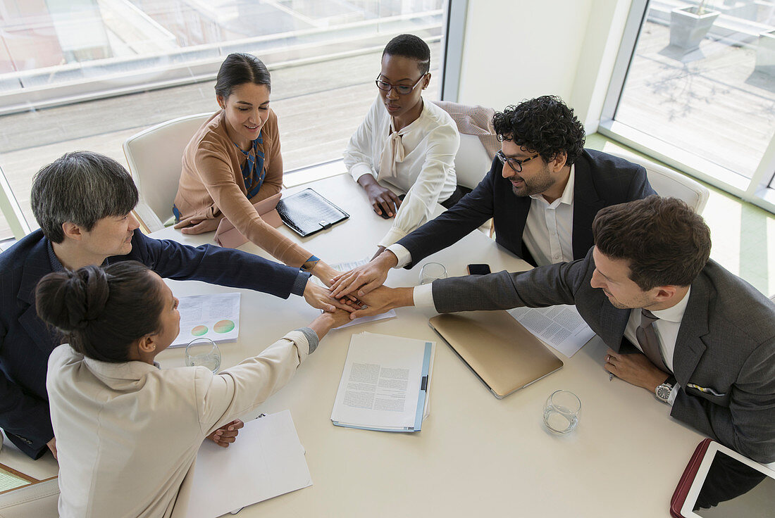 Business people joining hands in conference room meeting