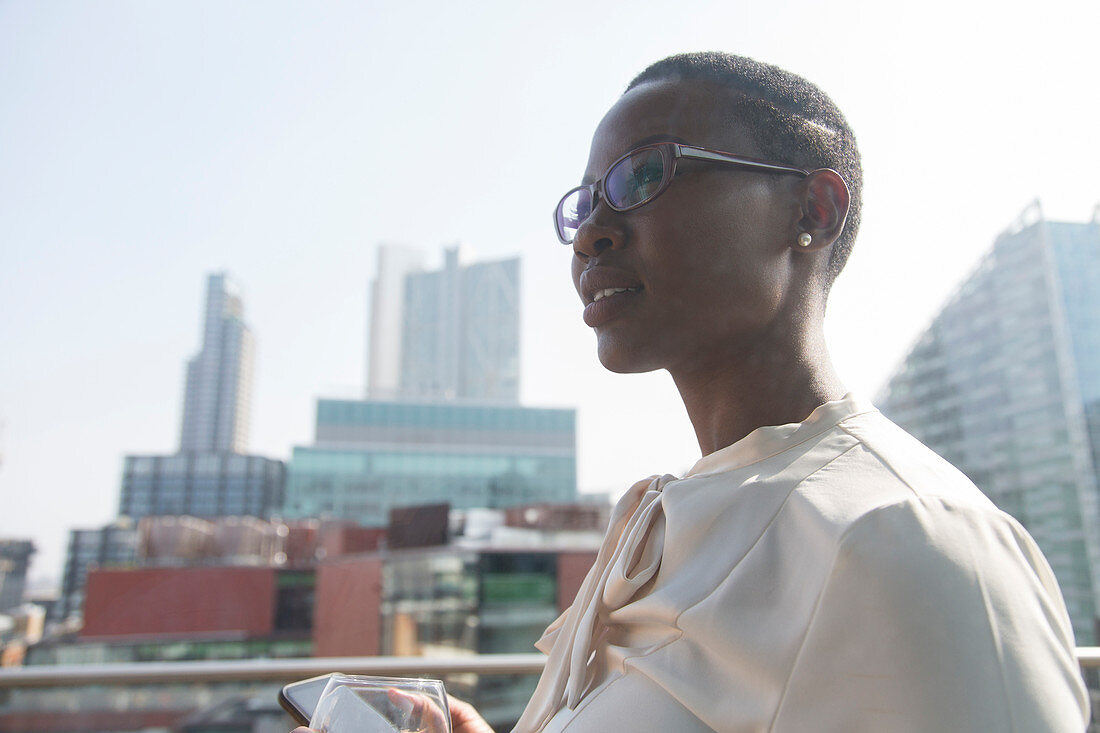 Ambitious, businesswoman on sunny, urban balcony