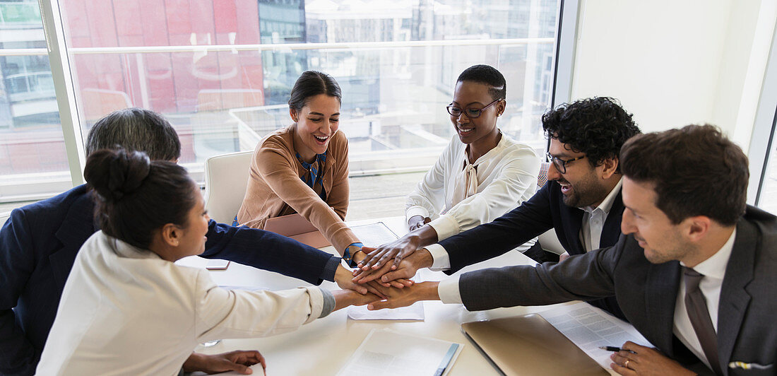 Business people joining hands in conference room meeting