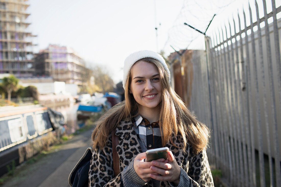 Portrait young woman with smart phone on urban sidewalk