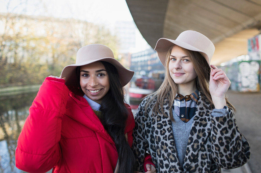 Portrait young women wearing fedoras along canal