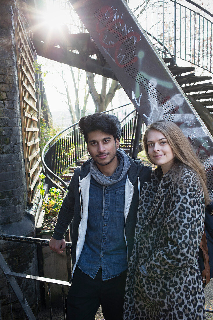Portrait young couple next to urban stairs