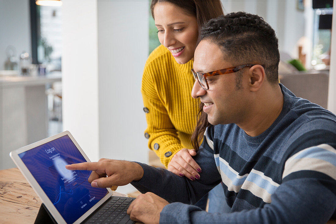 Couple using digital tablet, logging on with fingerprint