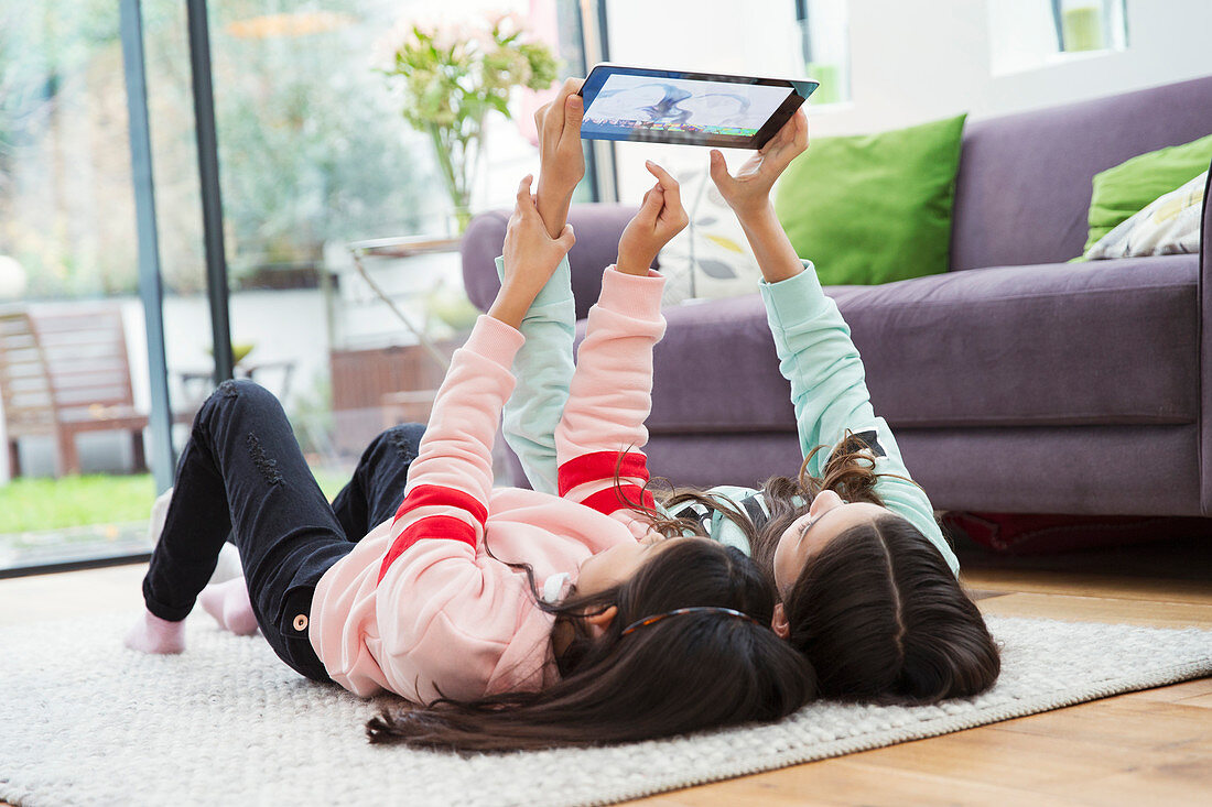 Girls taking selfie with tablet on living room floor