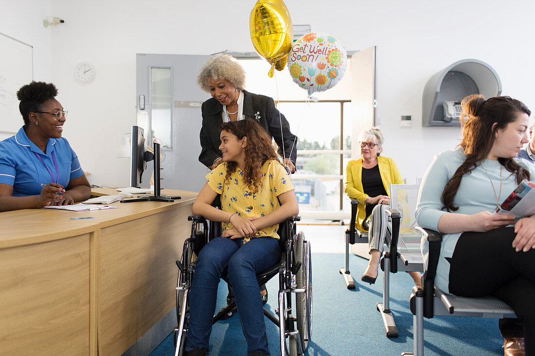 Female receptionist greeting girl patient in wheelchair