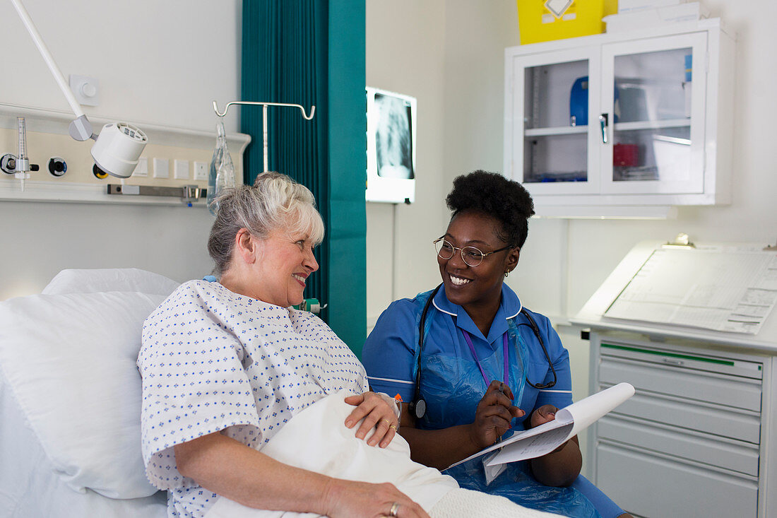 Female nurse talking with senior patient in hospital room