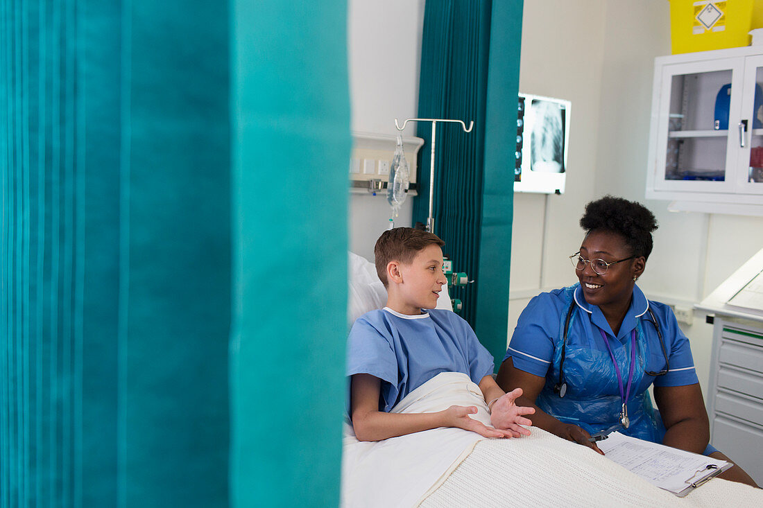 Female nurse talking to boy patient in hospital room