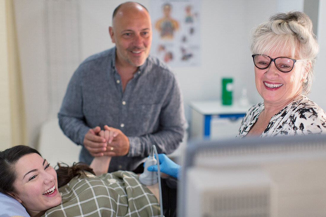 Technician performing ultrasound for happy pregnant couple