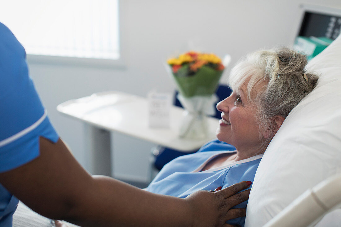 Nurse comforting woman resting in hospital bed