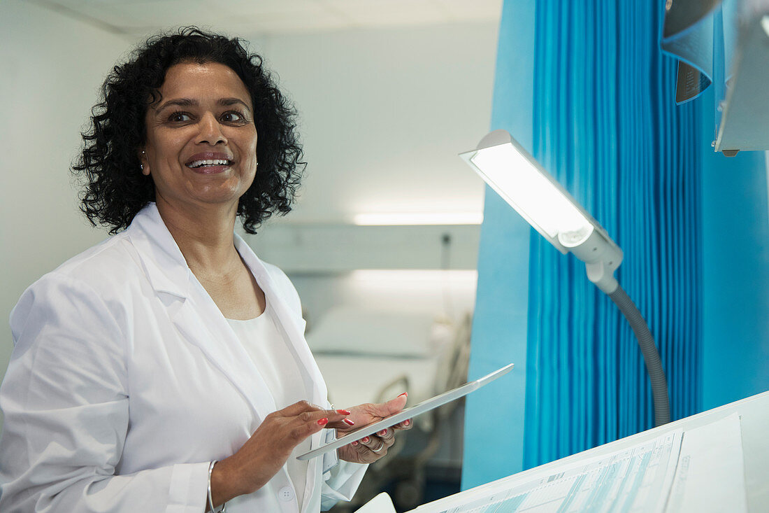 Smiling doctor using digital tablet in hospital room