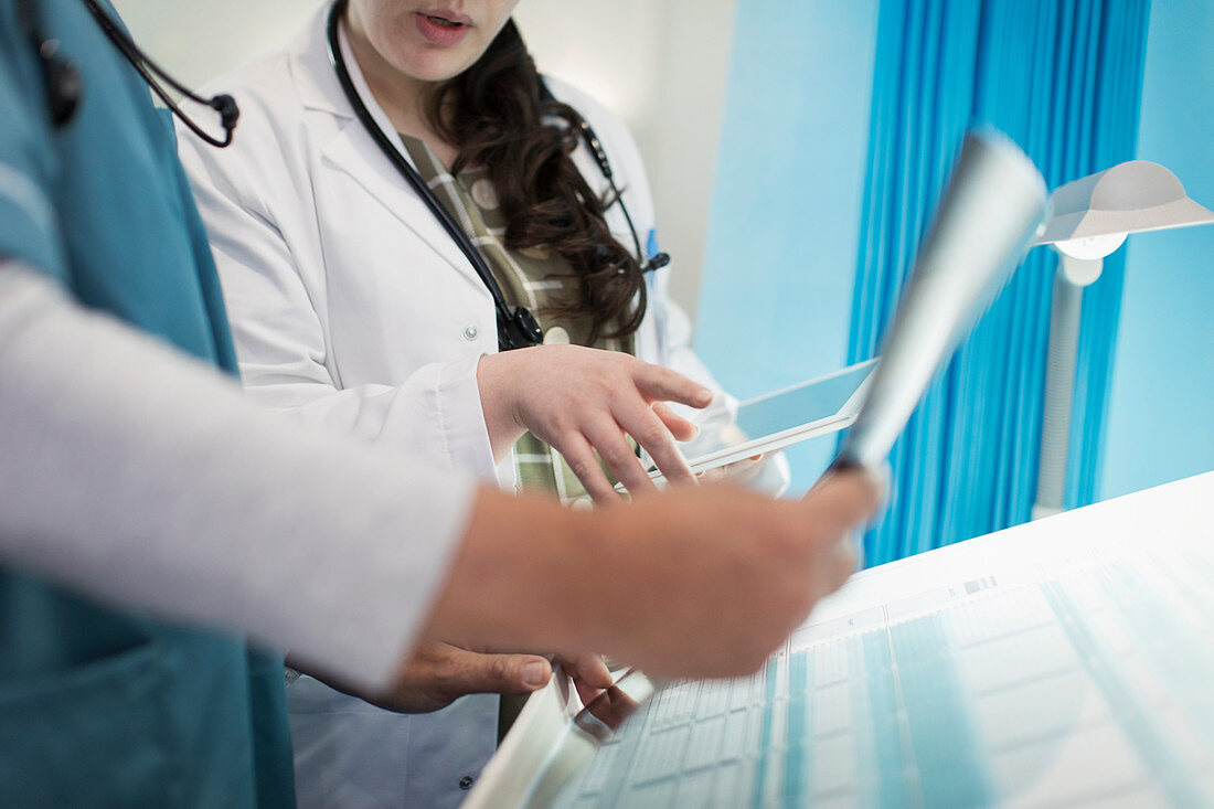 Doctors with tablet discussing x-ray in hospital room