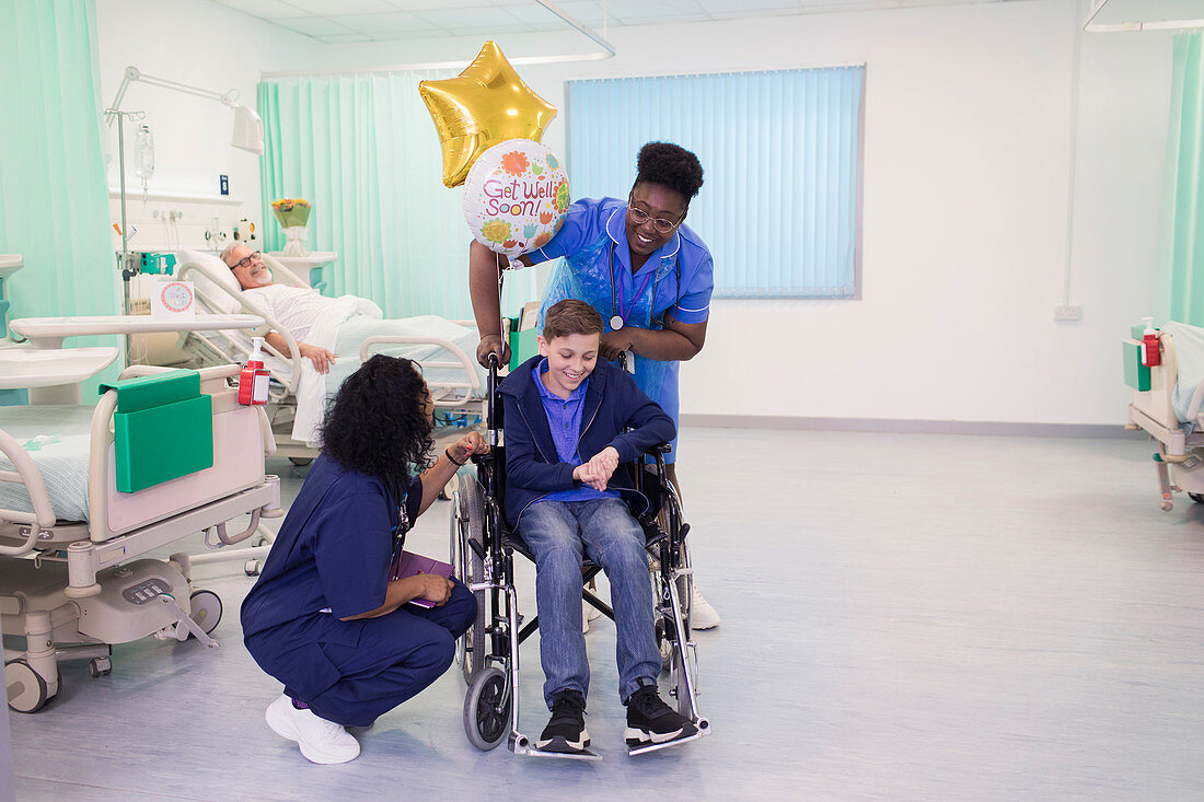 Doctor and nurse pushing boy patient in wheelchair