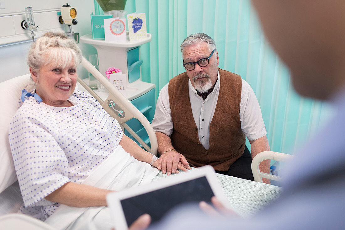 Doctor with tablet talking with couple in hospital room