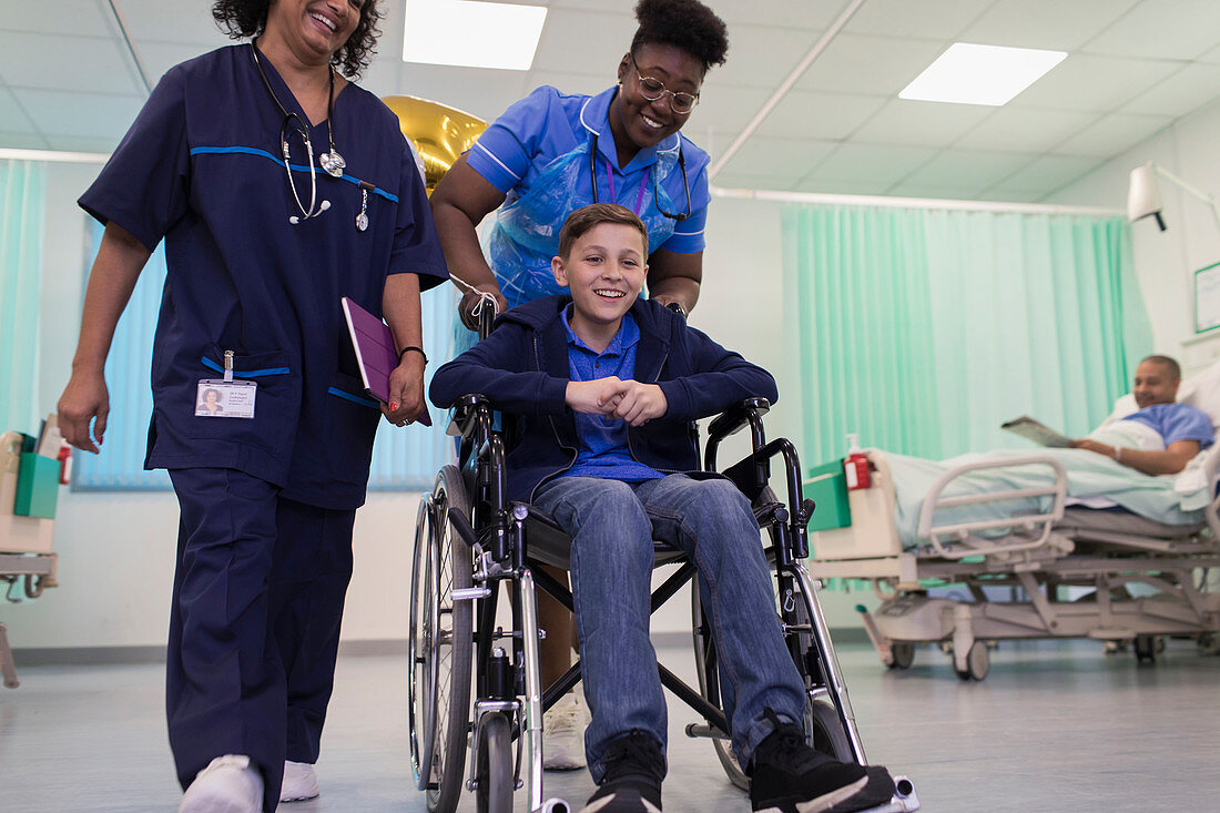 Doctor and nurse pushing boy patient in wheelchair