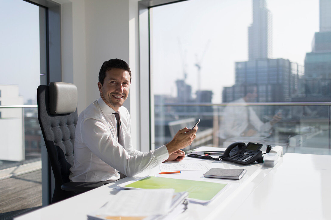 Portrait businessman using smart phone in highrise office
