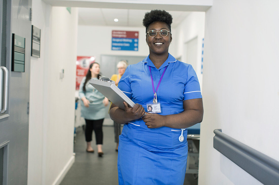 Portrait nurse with medical chart in hospital corridor