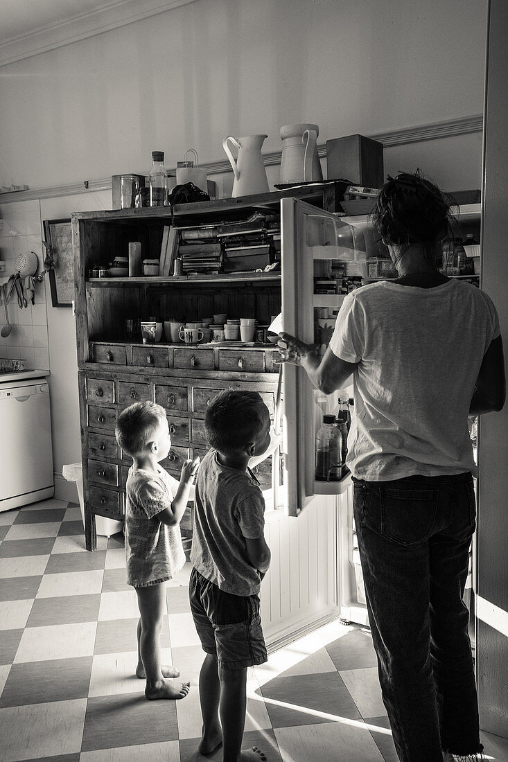 Family standing at open refrigerator in kitchen