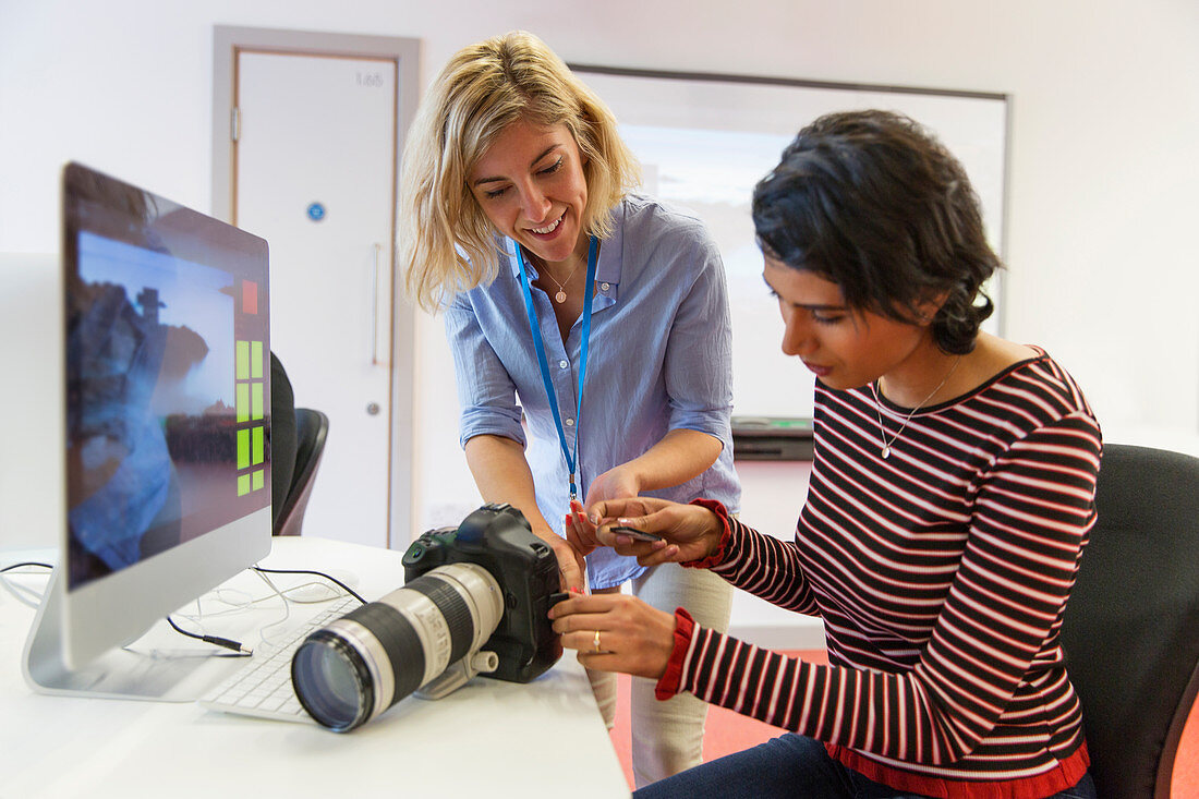 Female photographer teaching student how to use SLR camera