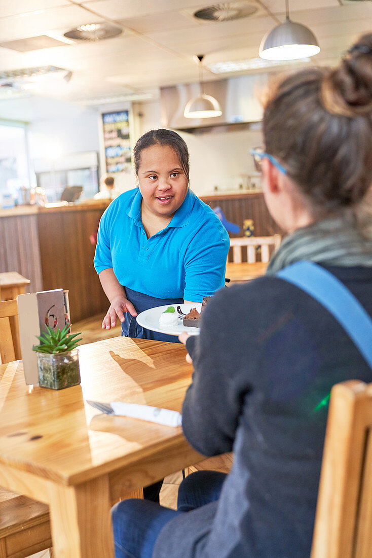 Young server with Down Syndrome serving food in cafe