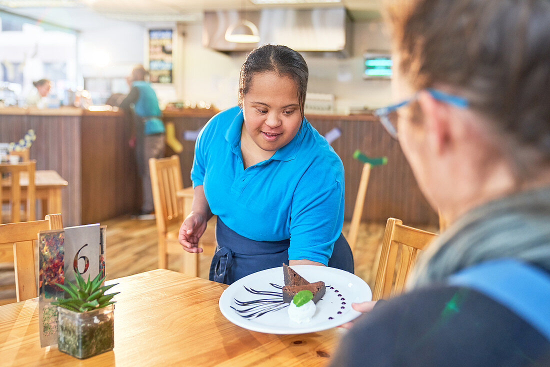 Young woman with Down Syndrome serving dessert in cafe